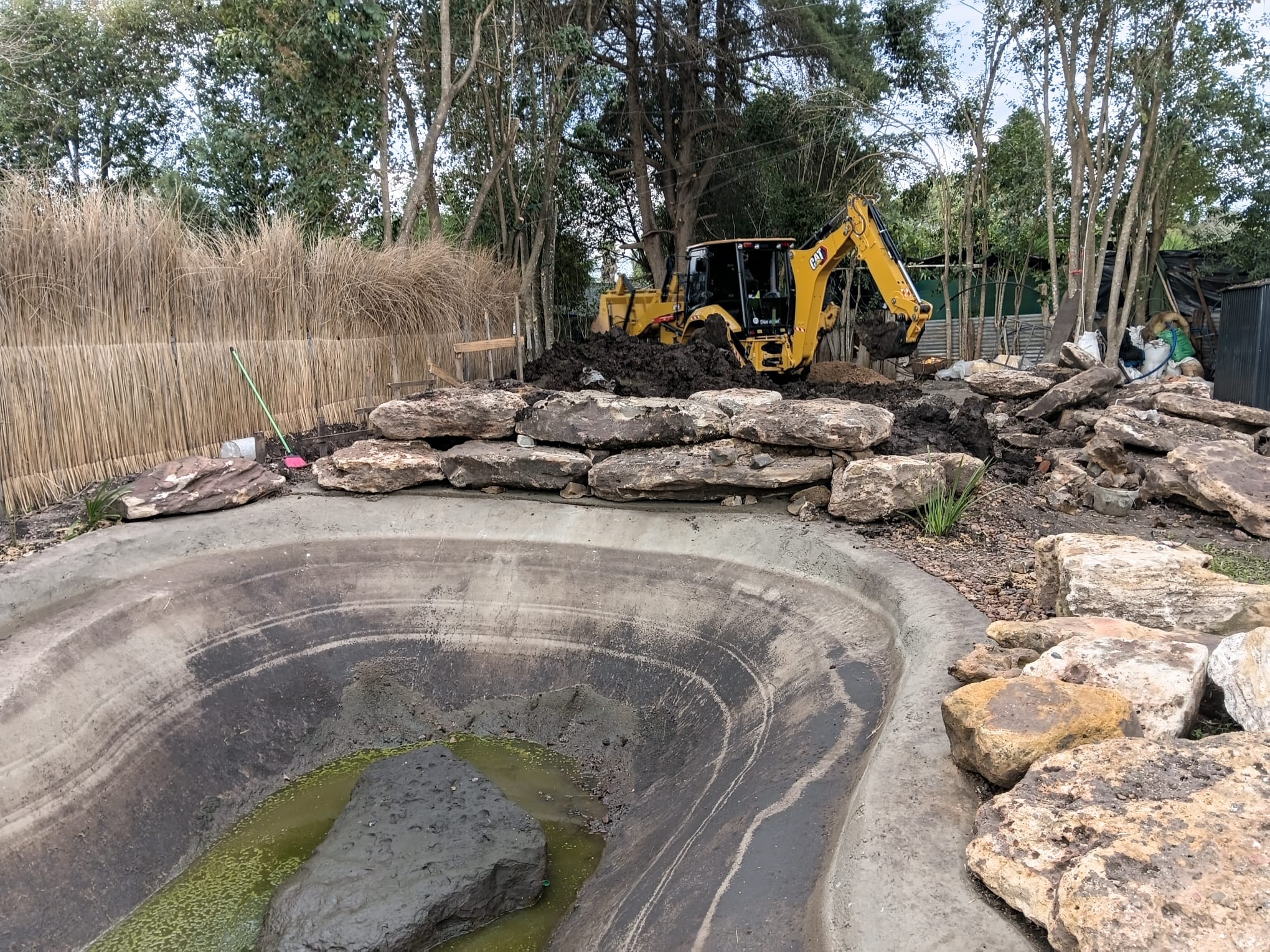 Trabajo con retroexcavadora junto a estanque